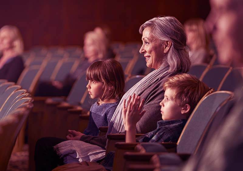 mulher mais idosa com seus netos assistindo a um filme no cinema